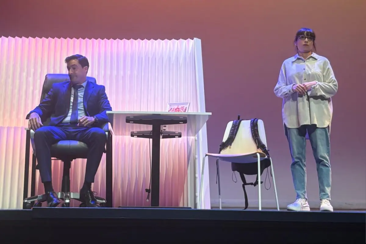 Protagonistas de la obra de teatro El Crédito dialogando intensamente sentados frente a un escritorio.